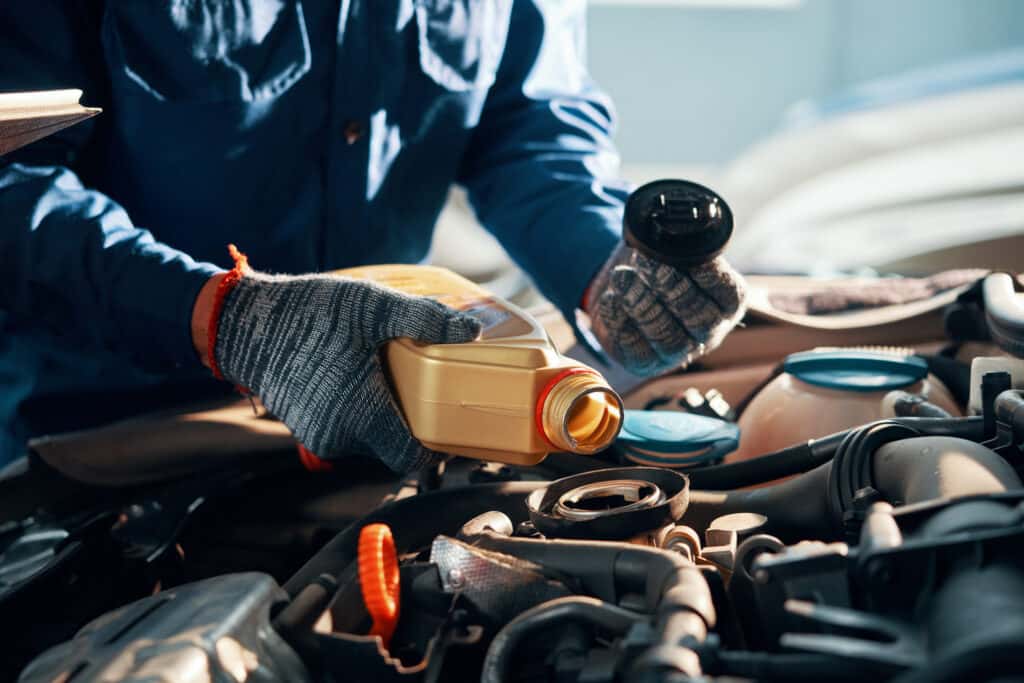 Mechanic adding fluids to a car engine
