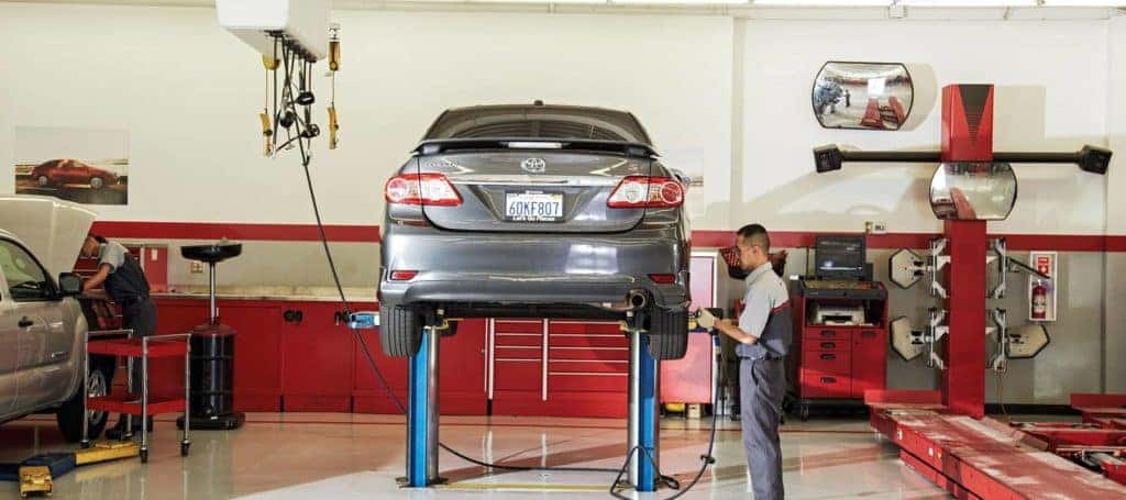 a mechanic inspecting the tires of a raised toyota