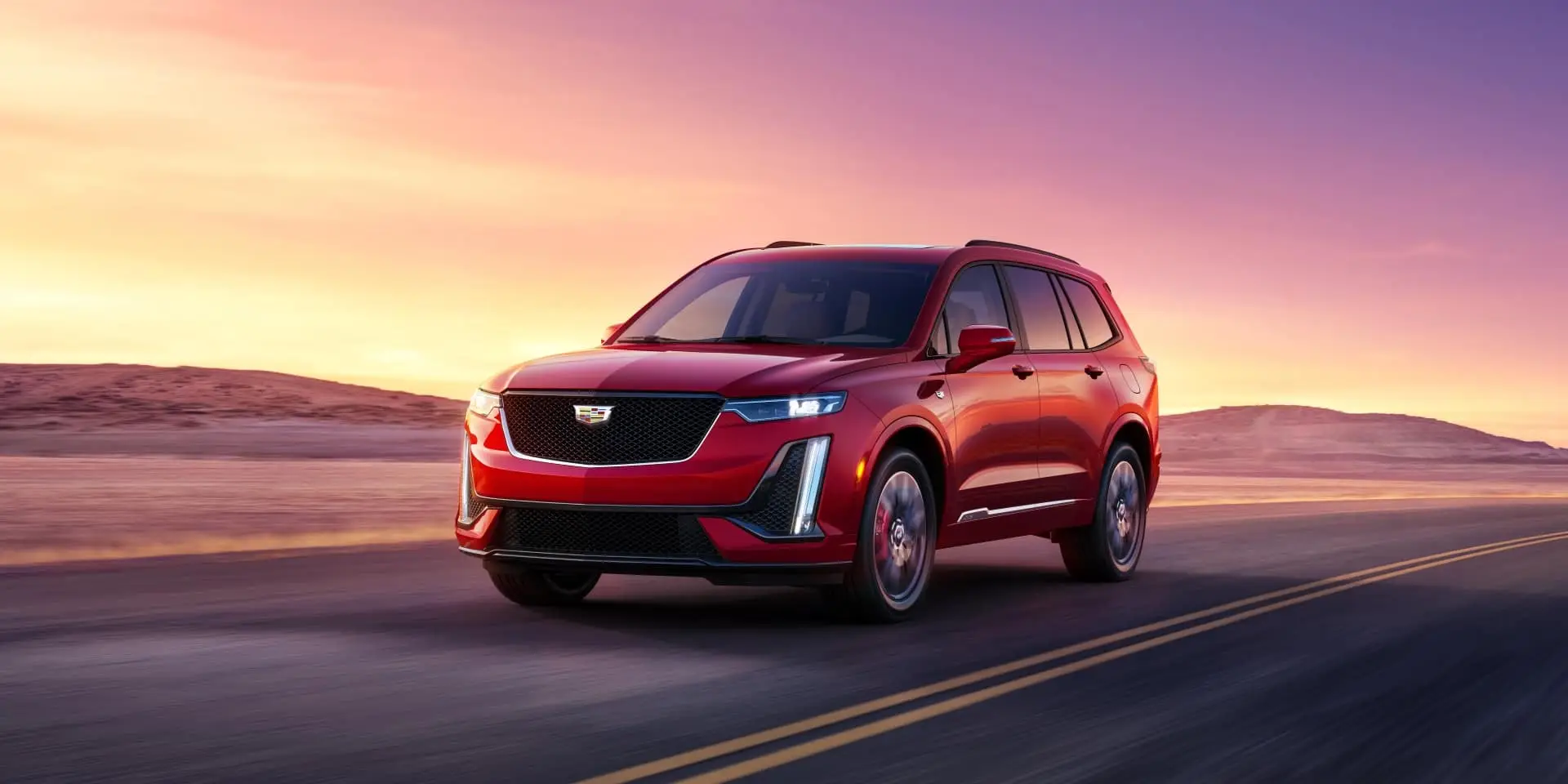 2024 Cadillac XT6 Sport in red in motion on a road.