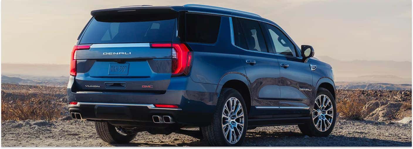 Rear three-quarter view of a dark blue 2026 GMC Yukon XL Denali parked in a desert landscape.