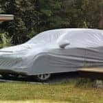 man putting cover over car