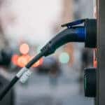 Close-up of an electric car charging station with a car plugged in by Ivan Radic is licensed with CC BY 2.0 DEED