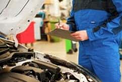 Man with clipboard working on a car