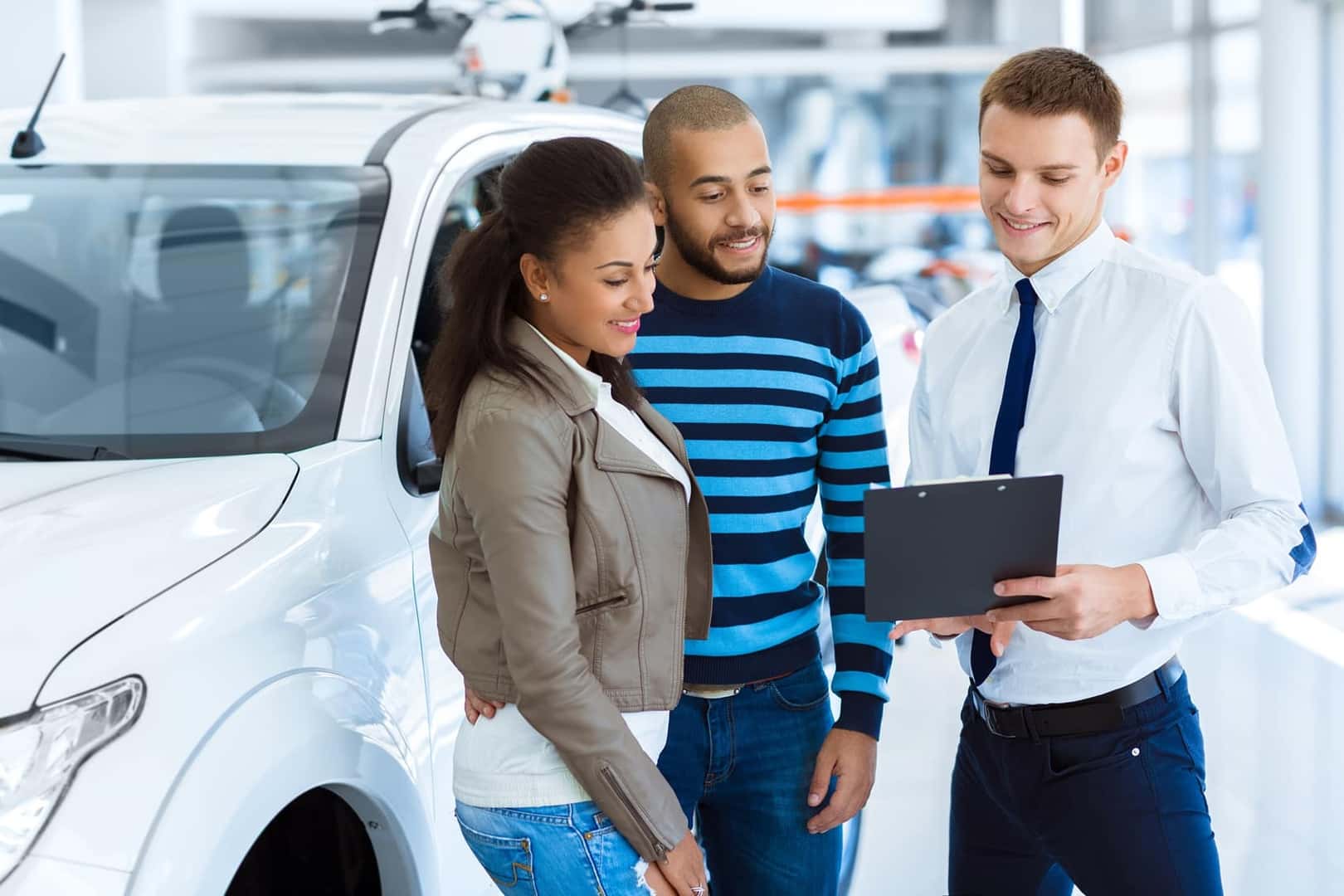 Couple receiving car-buying assistance from a car sales consultant at a dealership
