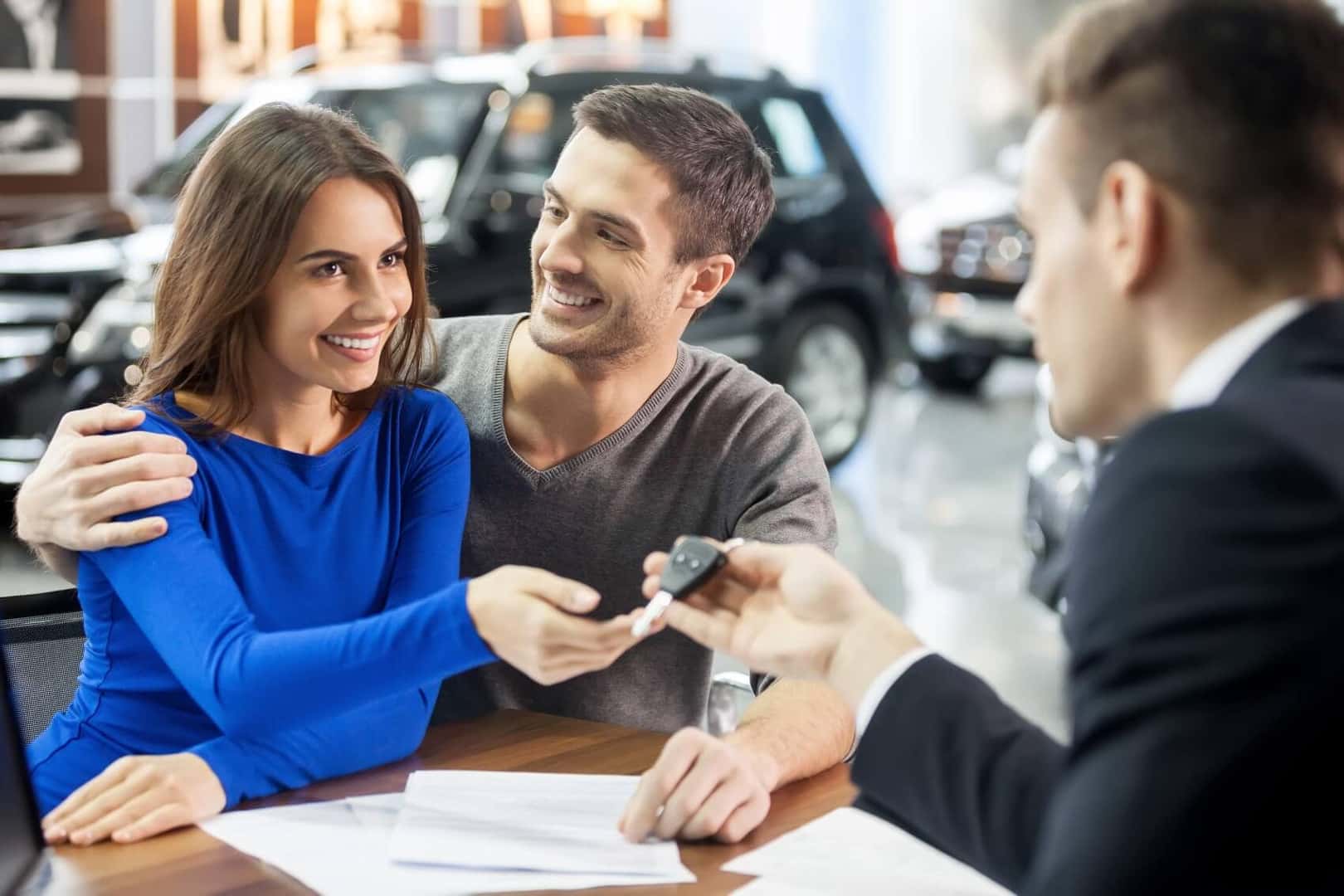 Cadillac Dealer employee with customers handing them a key