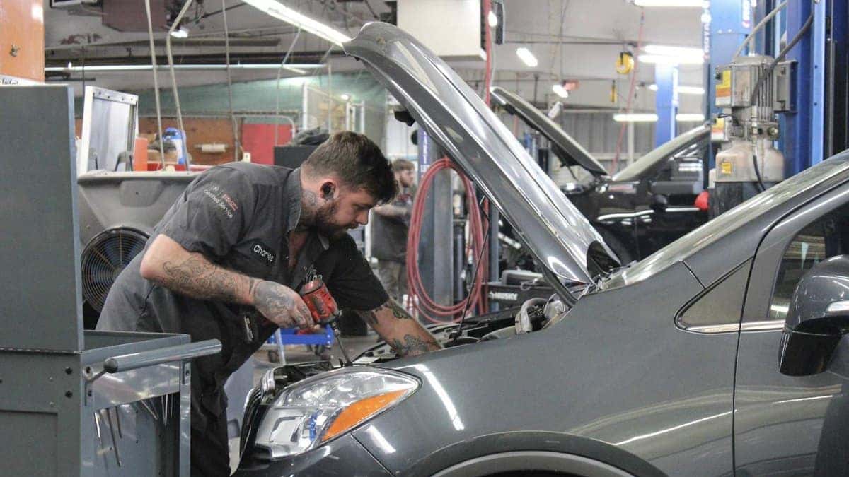 Technician inspecting a Buick Encore under the hood at Jim Taylor Buick GMC in Monroe, LA