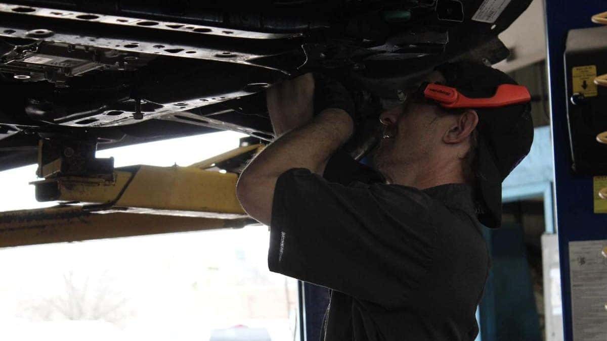 Technician inspecting the underside of a vehicle on a lift at Jim Taylor Buick GMC in Monroe, LA
