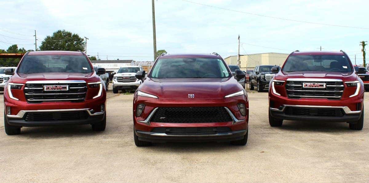 Two red GMC Acadia SUVs and a red Buick Envista ST on the Jim Taylor Buick GMC lot in Monroe, LA