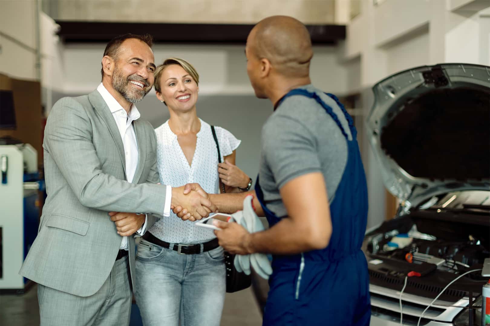 Volkswagen Certified technician shaking hands with couple after reviewing maintenance repairs