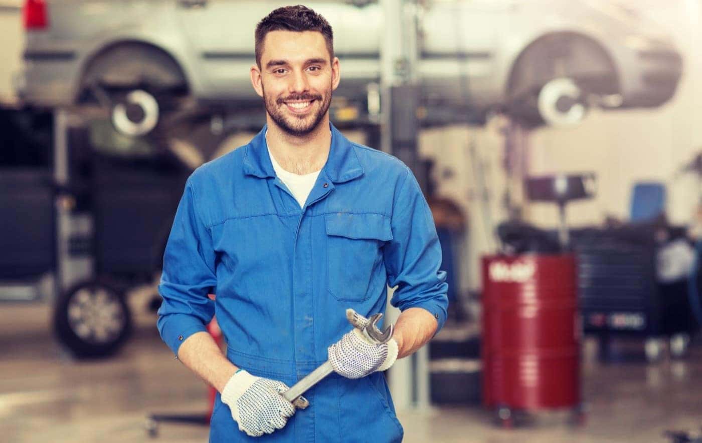 Volkswagen Certified Technician holding wrench and smiling before repairs in VW Service Center