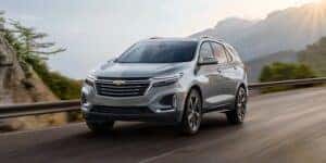 A silver 2024 Chevy Equinox SUV drives on a mouontain road