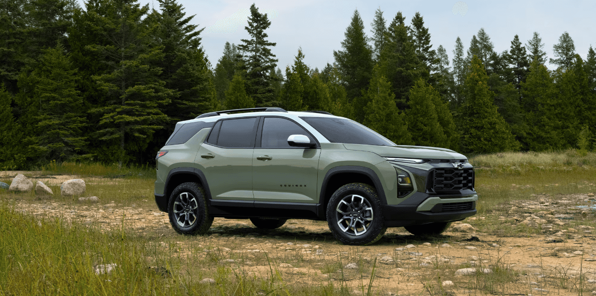 Green 2026 Chevrolet Equinox SUV parked on a rugged trail surrounded by pine trees