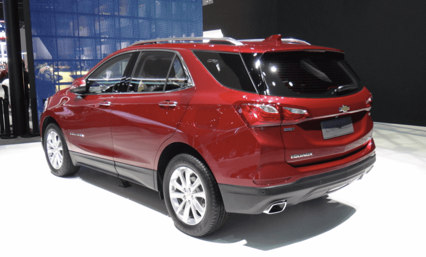Red Chevrolet Equinox SUV displayed indoors, showing rear and side profile under bright lighting