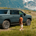 Family unloading a 2026 Chevrolet Suburban in a grassy mountain landscape