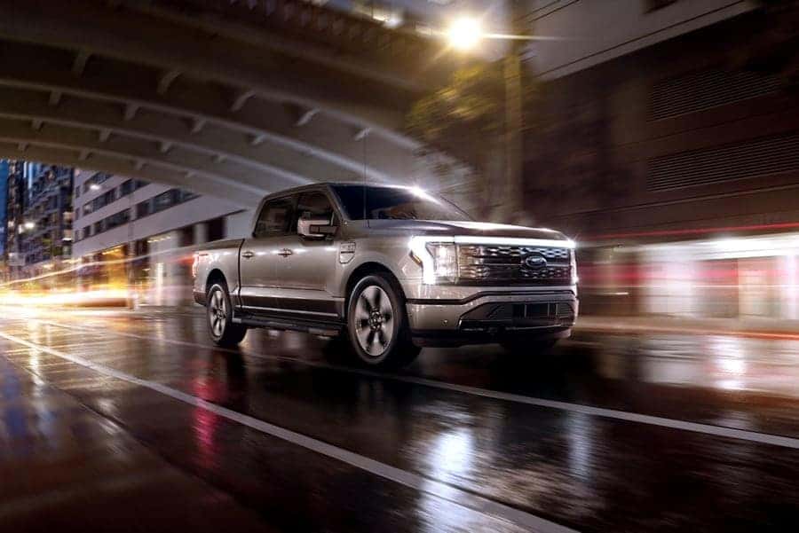 Silver Ford F-150 Lightning driving at night in a city
