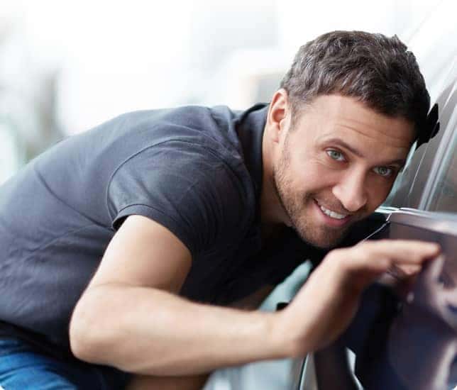 man inspecting outside of vehicle
