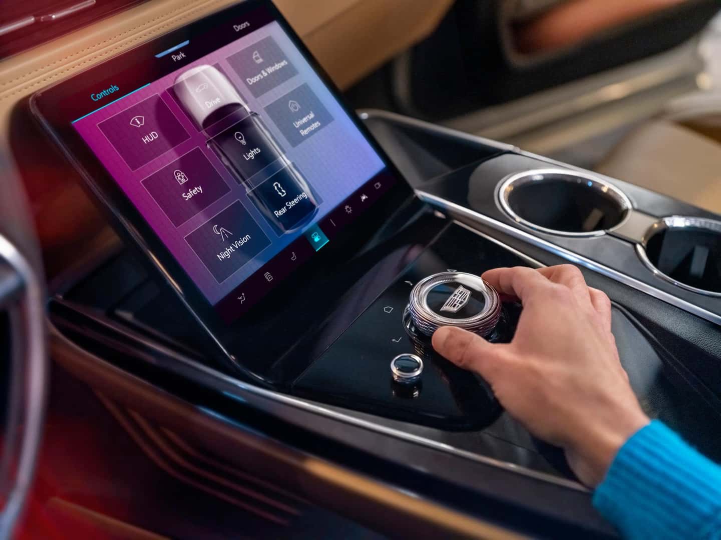 person controlling the knob of the center console inside the cadillac escalade iq