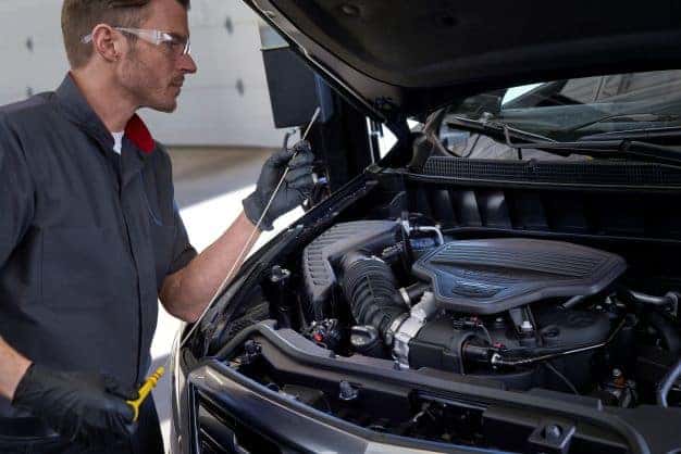 Cadillac Mechanic checking oil dipstick