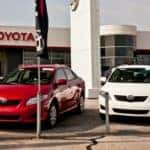 Two Toyotas sit outside of a Toyota dealership.