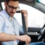 A man buckles his seatbelt in the front seat of his Toyota.