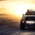 A Toyota truck in the foreground of an off road adventure with a sunset.