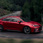 A red Toyota Corolla Hybrid turns around a curvy mountain road
