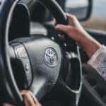 Hands positioned on a steering wheel of a beautiful Toyota Corolla.