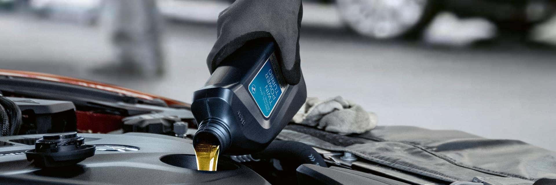 bmw service tech pouring oil into vehicle