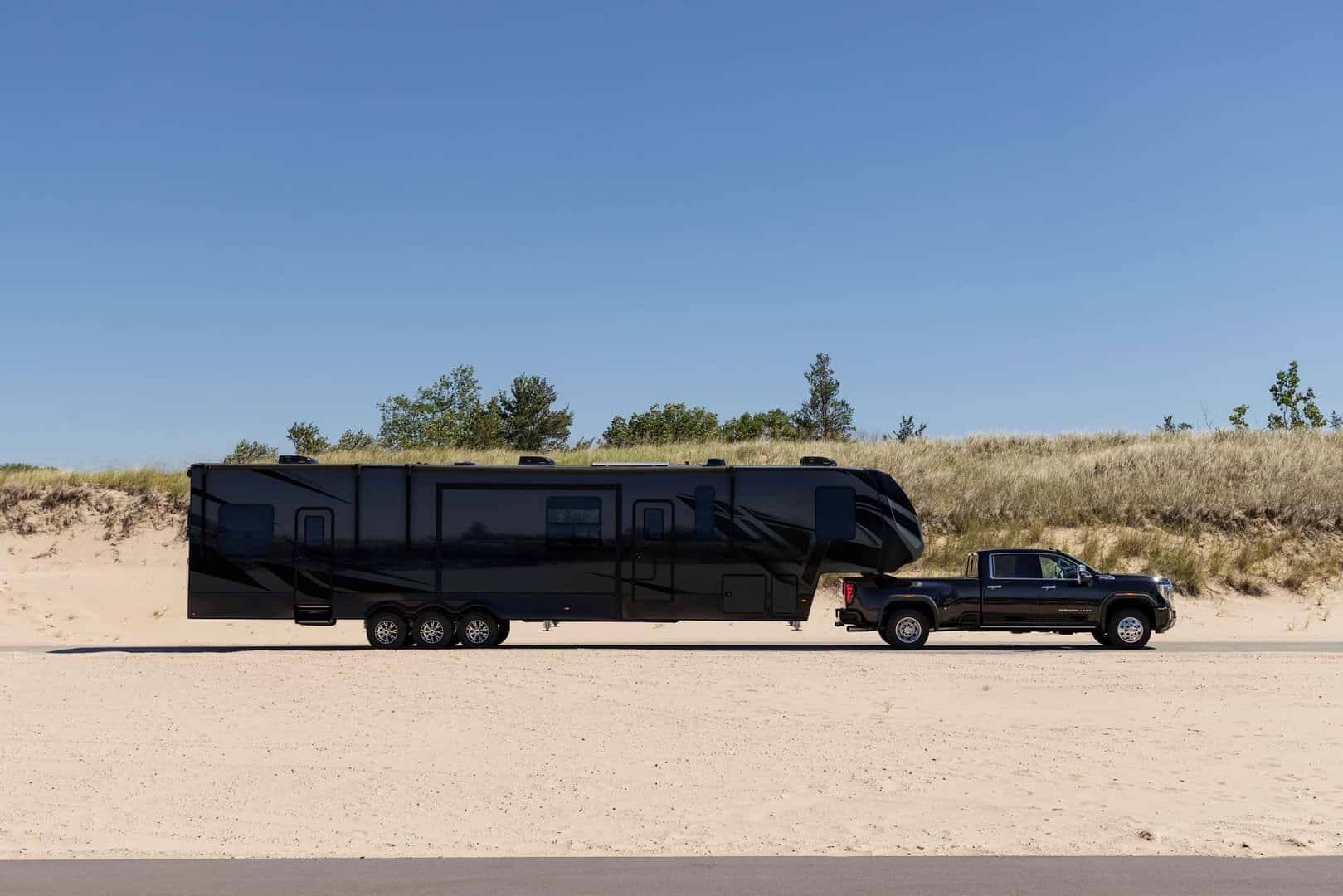 The Inspiring Side Profile Of The Tough 2024 GMC Sierra 3500 HD Denali, Pulling A Long Black Trailer With Grace