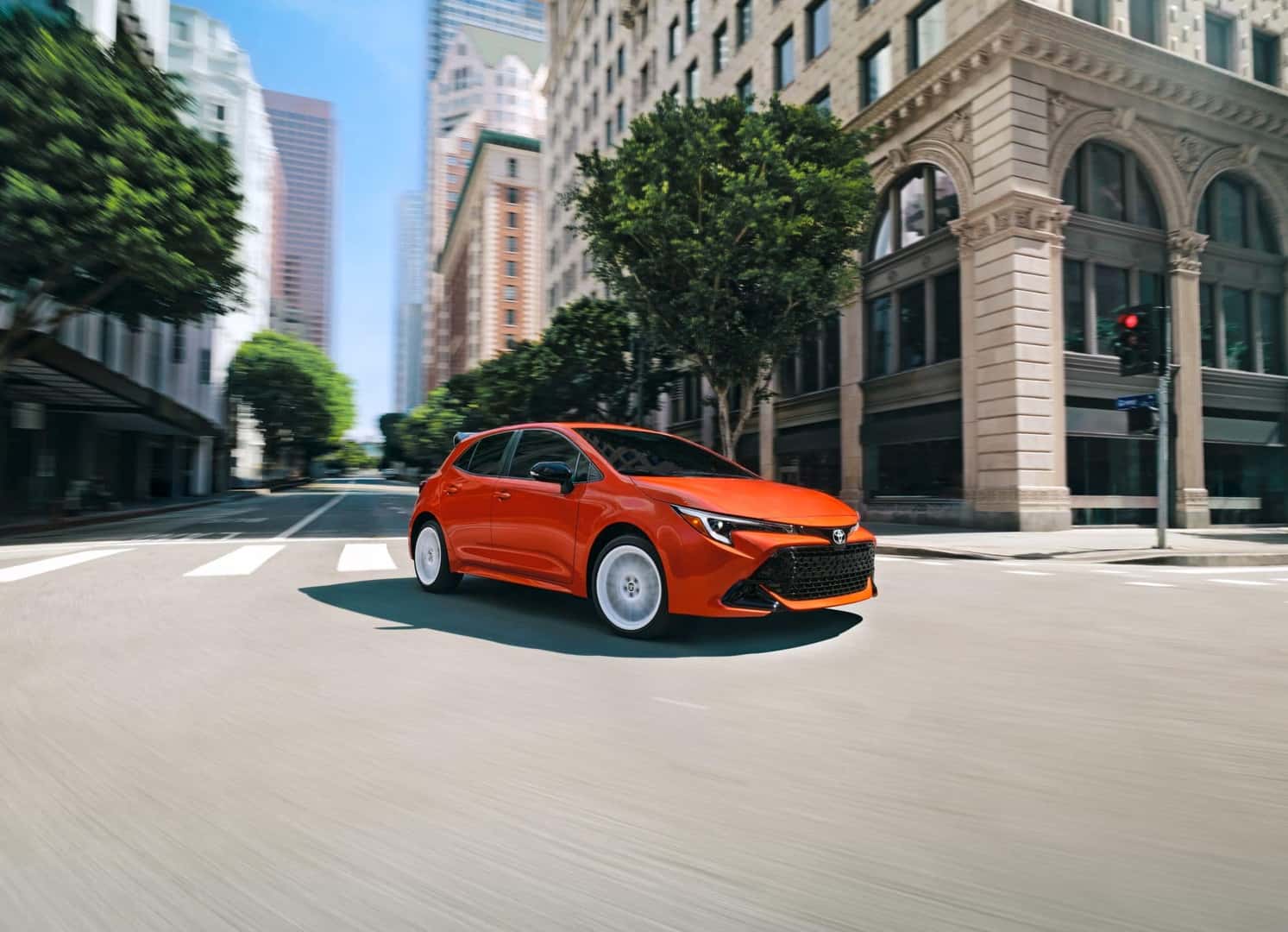 An Orange 2026 Corolla Hatchback FX Turning Gracefully At An Elegant City Intersection