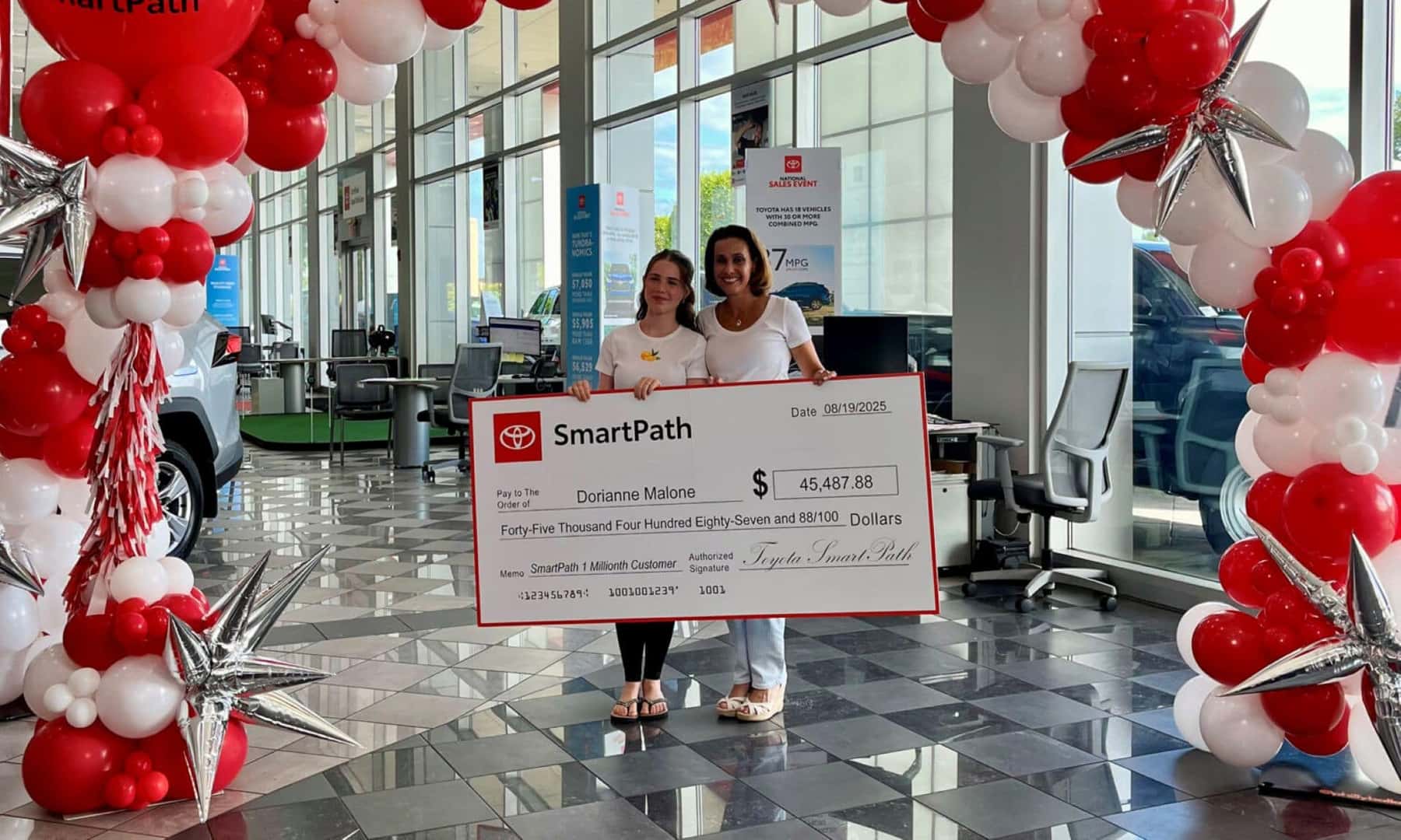The Millionth SmartPath Customer Photographed With The Signed Check, Under A Balloon Arch