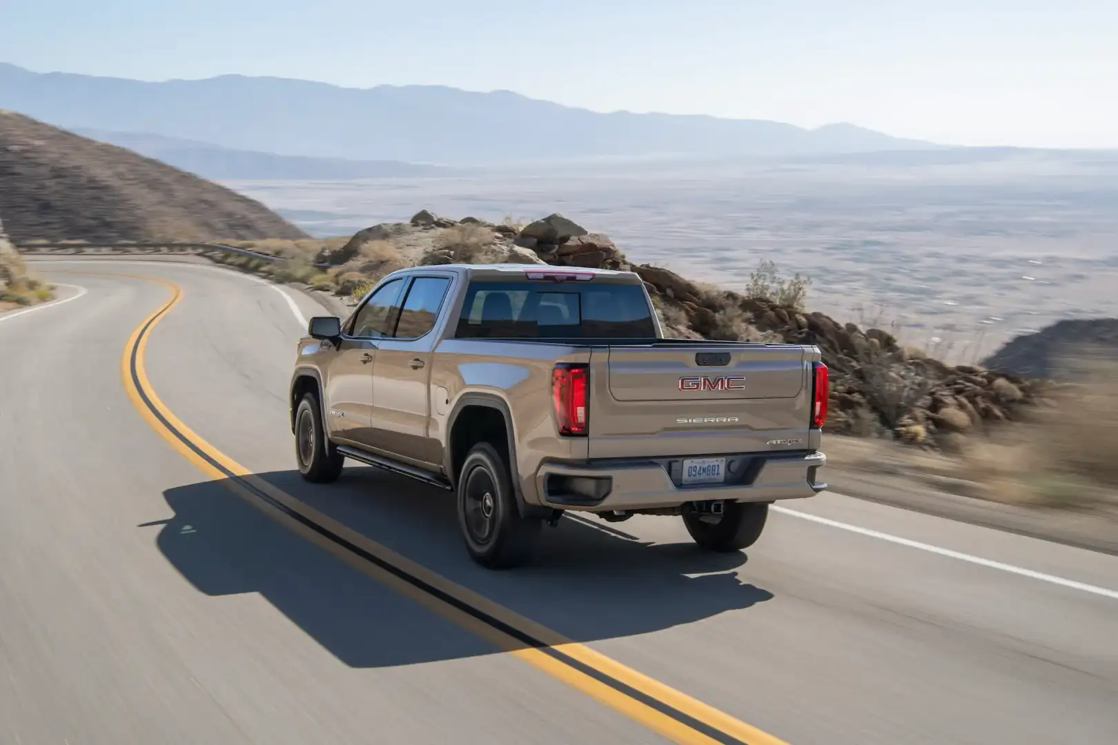 Rear view of the GMC Sierra driving on a mountain road