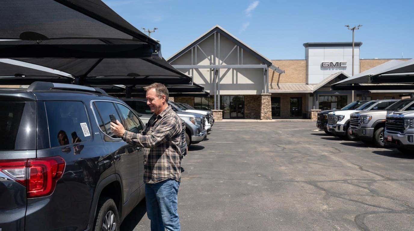 Shopper scanning a QR window sticker on a used SUV at Weld County Garage in Greeley to compare live upfront pricing