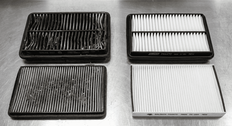 Two dirty air filters next to two clean replacements on the bench at Weld County Garage