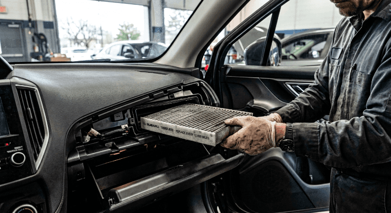 Technician removing a dirty cabin air filter from a Subaru at the Weld County Garage service department