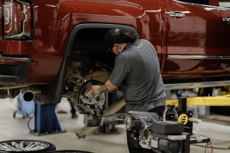 Weld County Garage technician replacing brake components on a GMC pickup with the wheel removed