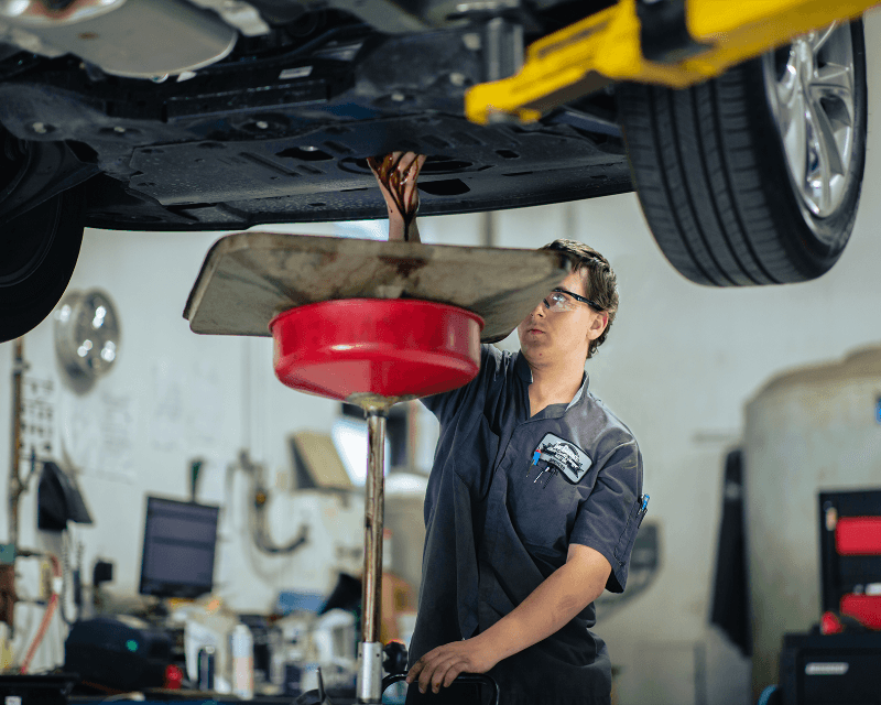 Technician draining engine oil during an oil change at Weld County Garage in Greeley